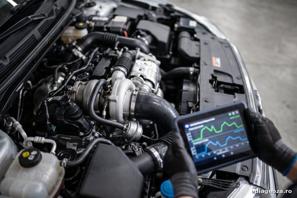 Turbina unui motor diesel cu furtunul de presiune si actuatorul, langa un tester care arata presiunea de supraalimentare ceruta si reala